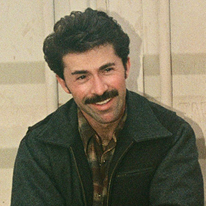 Headshot of Albert, a smiling man with a mustache and dark, curly hair wearing a jacket.
