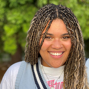 Headshot of Caitlan Moore, a smiling woman with braided hair and blonde highlights.