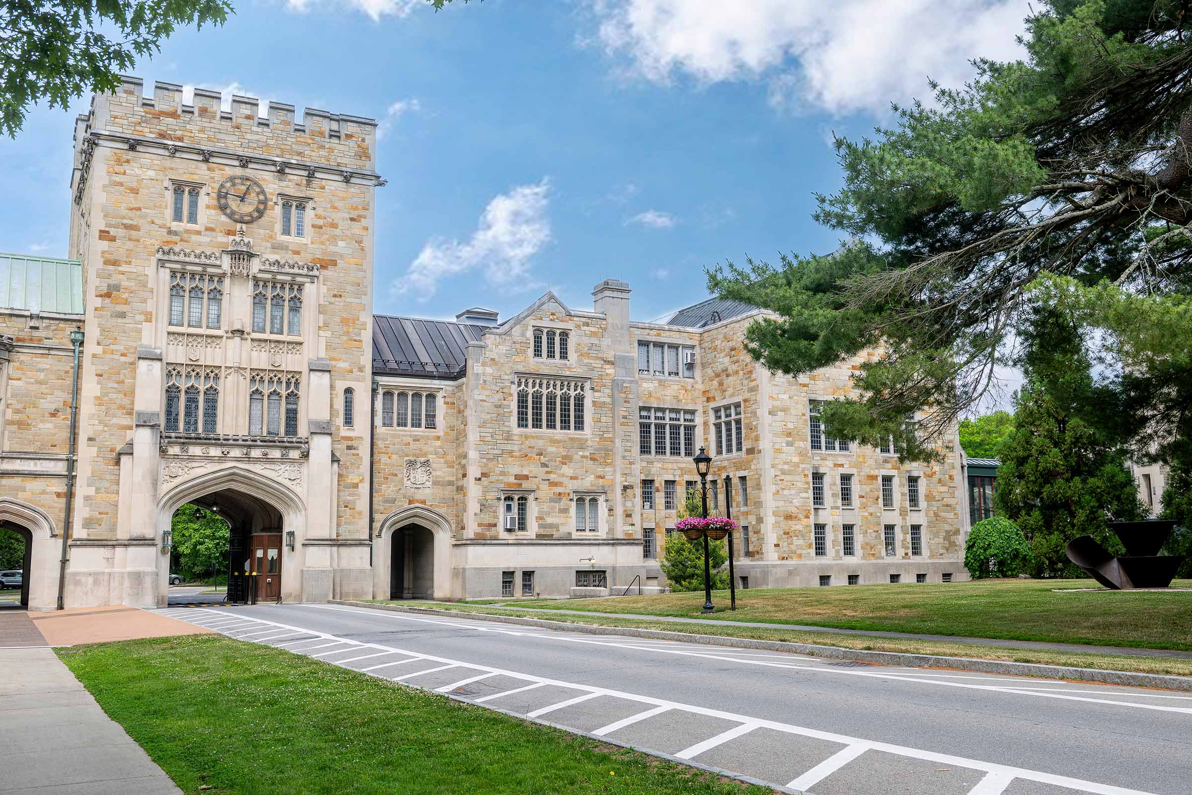 A large stone Gothic-style building with a clock-face tower over an arched driveway.